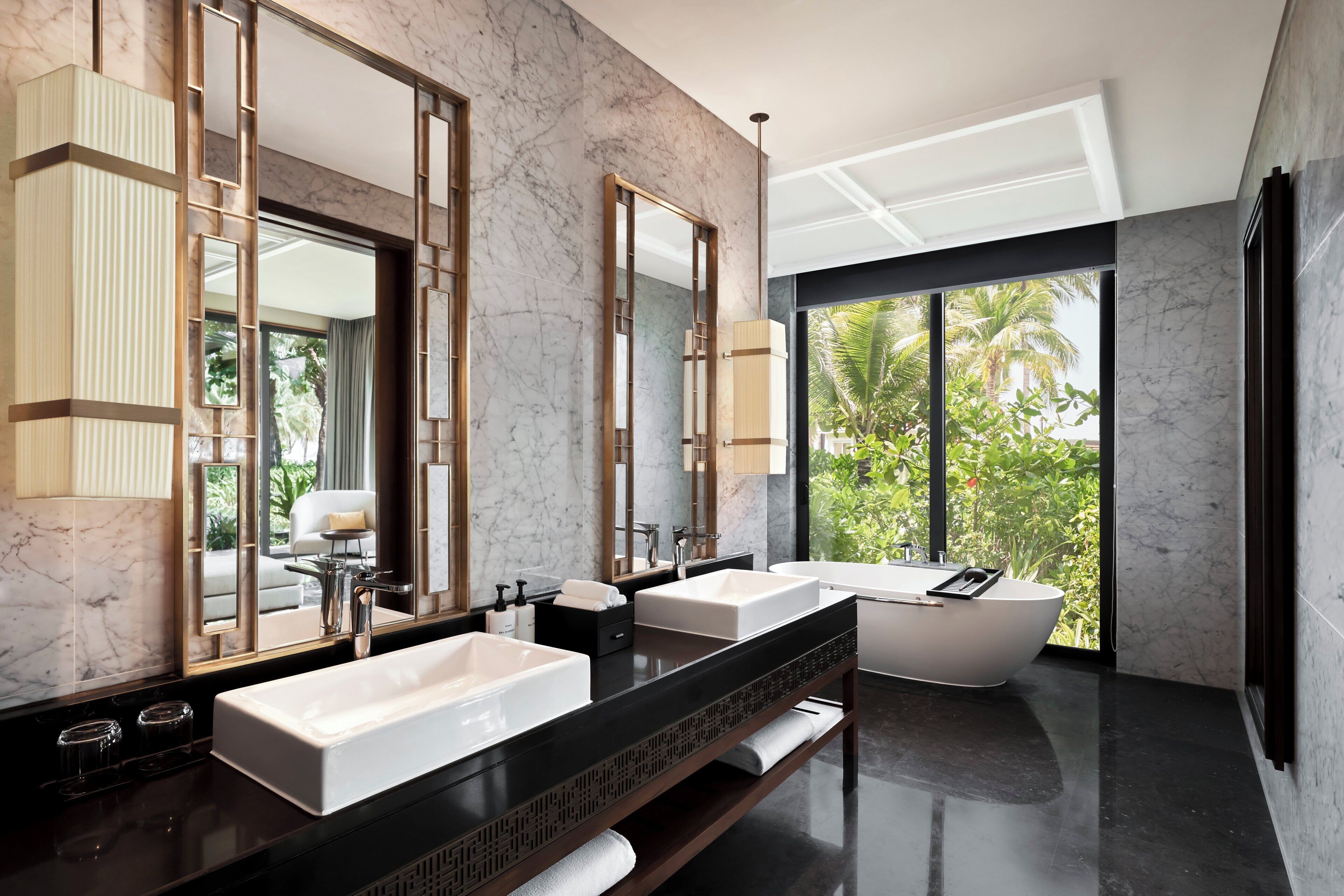 A modern bathroom with two sinks, a large mirror, and a bathtub.
