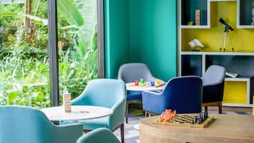 A room with two blue chairs, a small round table, and a chessboard.