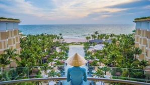 Un balcón de resort con vista al océano y palmeras.