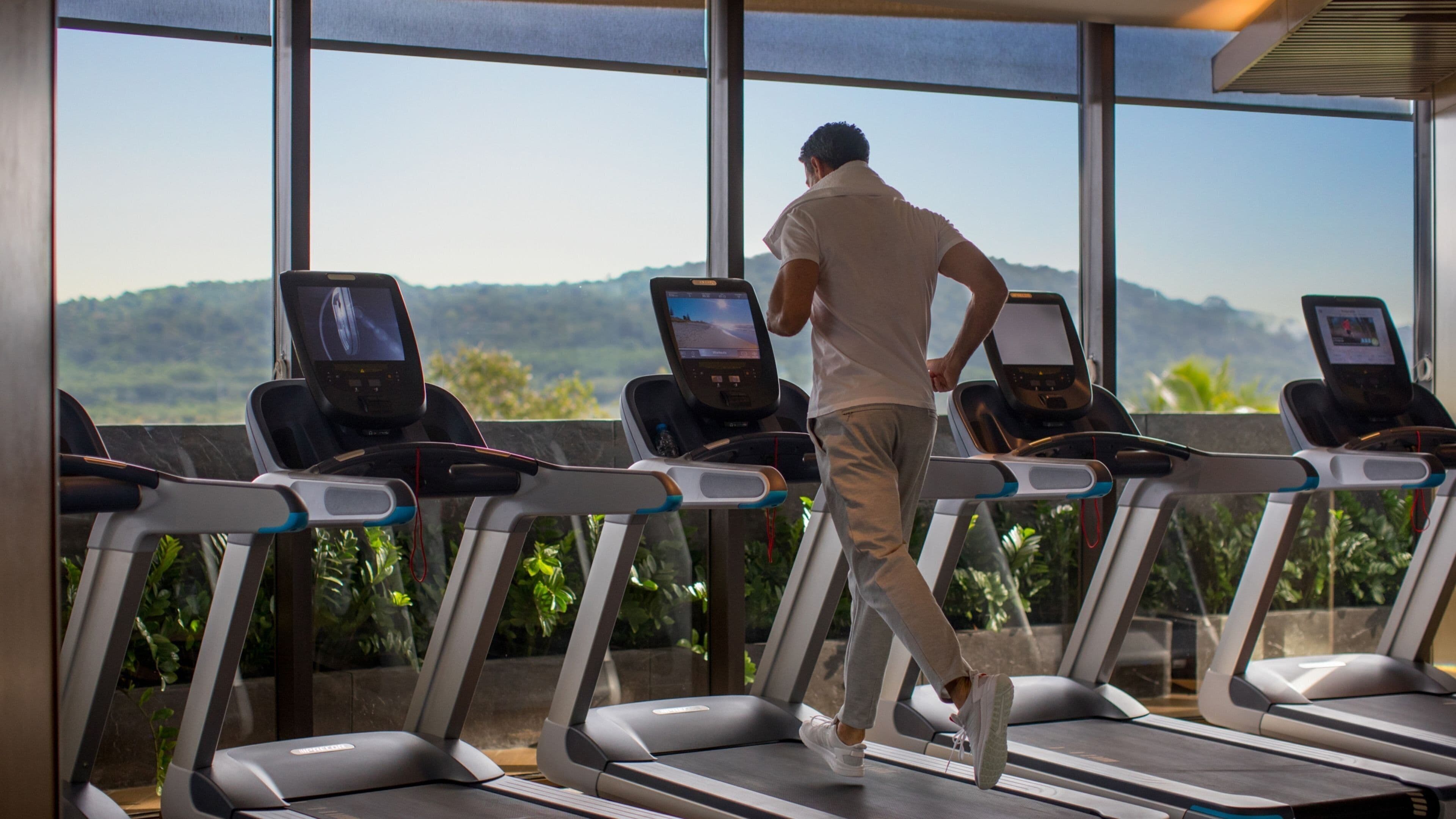 A gym with treadmills and large windows offering a view of a mountainous landscape.