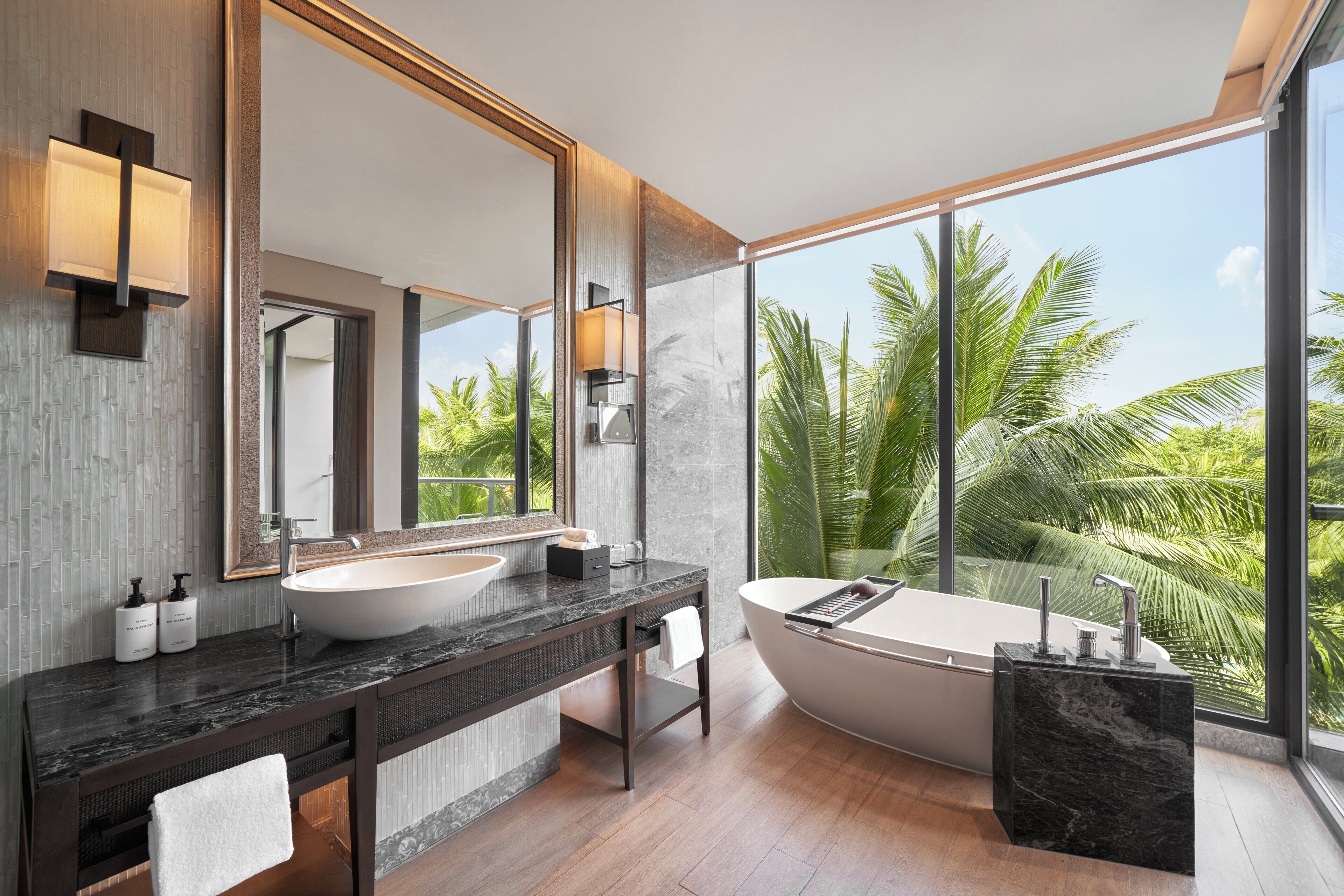 A modern bathroom with a large bathtub, two sinks, and a large mirror.