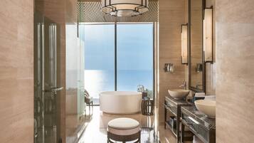 Un baño moderno con una bañera grande, un taburete redondo y un tocador con lavabo.