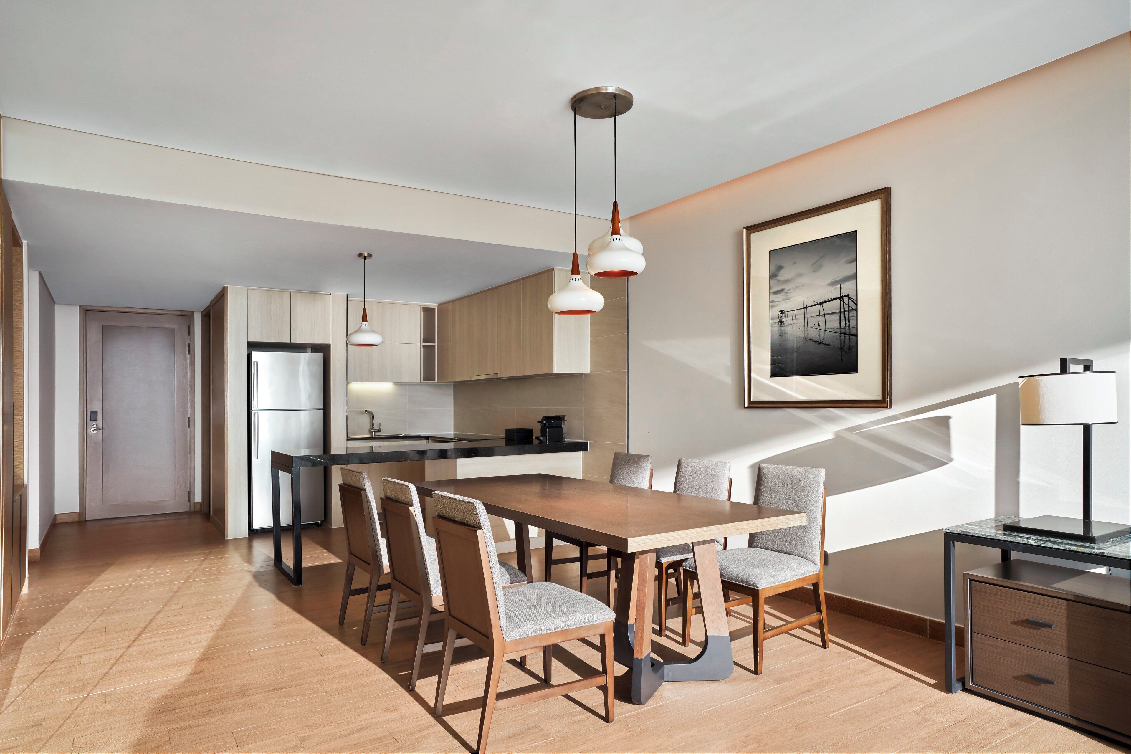 Une cuisine moderne dotée d’un îlot central, d’un coin repas avec une table et des chaises en bois, et d’un escalier menant à un niveau supérieur.
