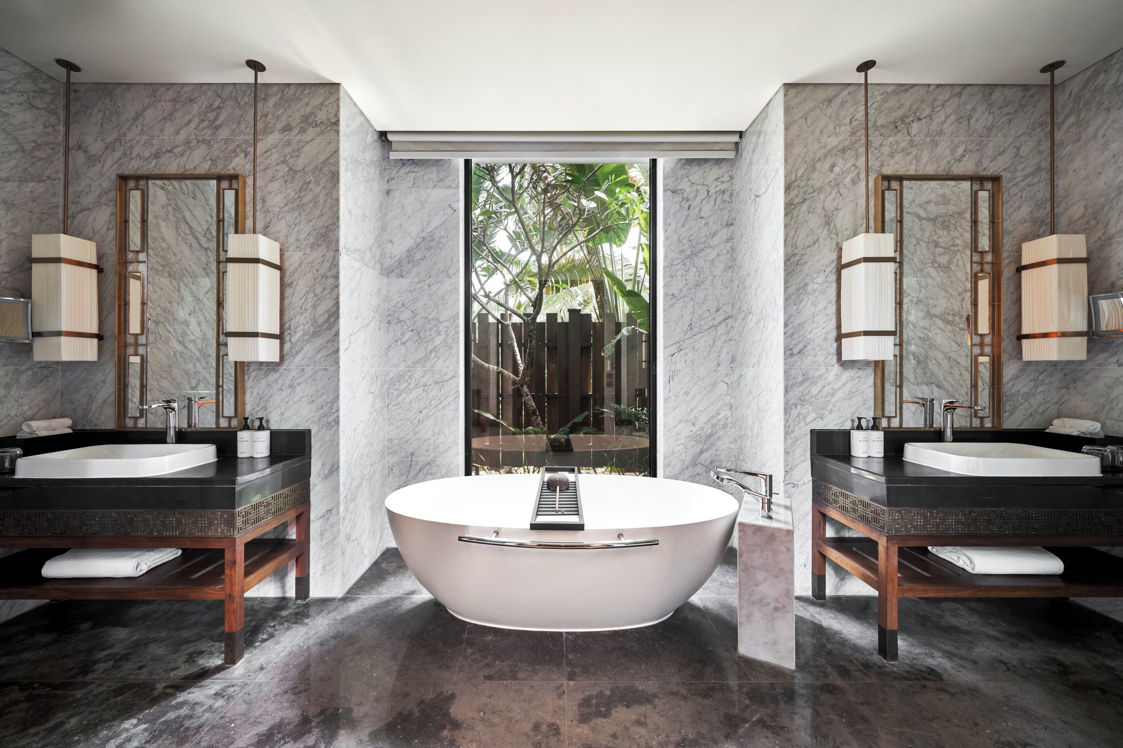 A modern bathroom with two sinks, a freestanding bathtub, and a large mirror.