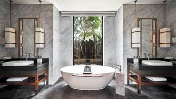 A modern bathroom with two sinks, a freestanding bathtub, and a large mirror.