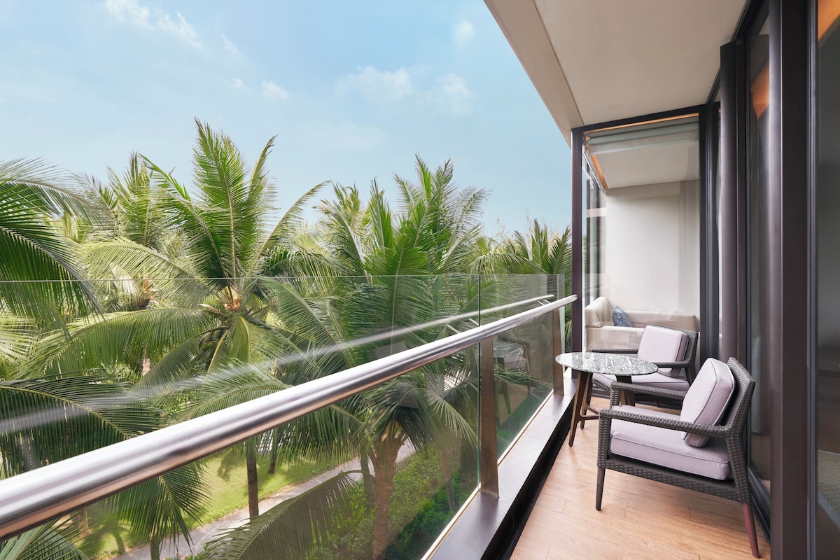 A balcony with a glass railing, a wicker sofa, and a small table.