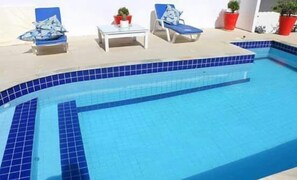 Alberca al aire libre, sombrillas en la alberca y camastros