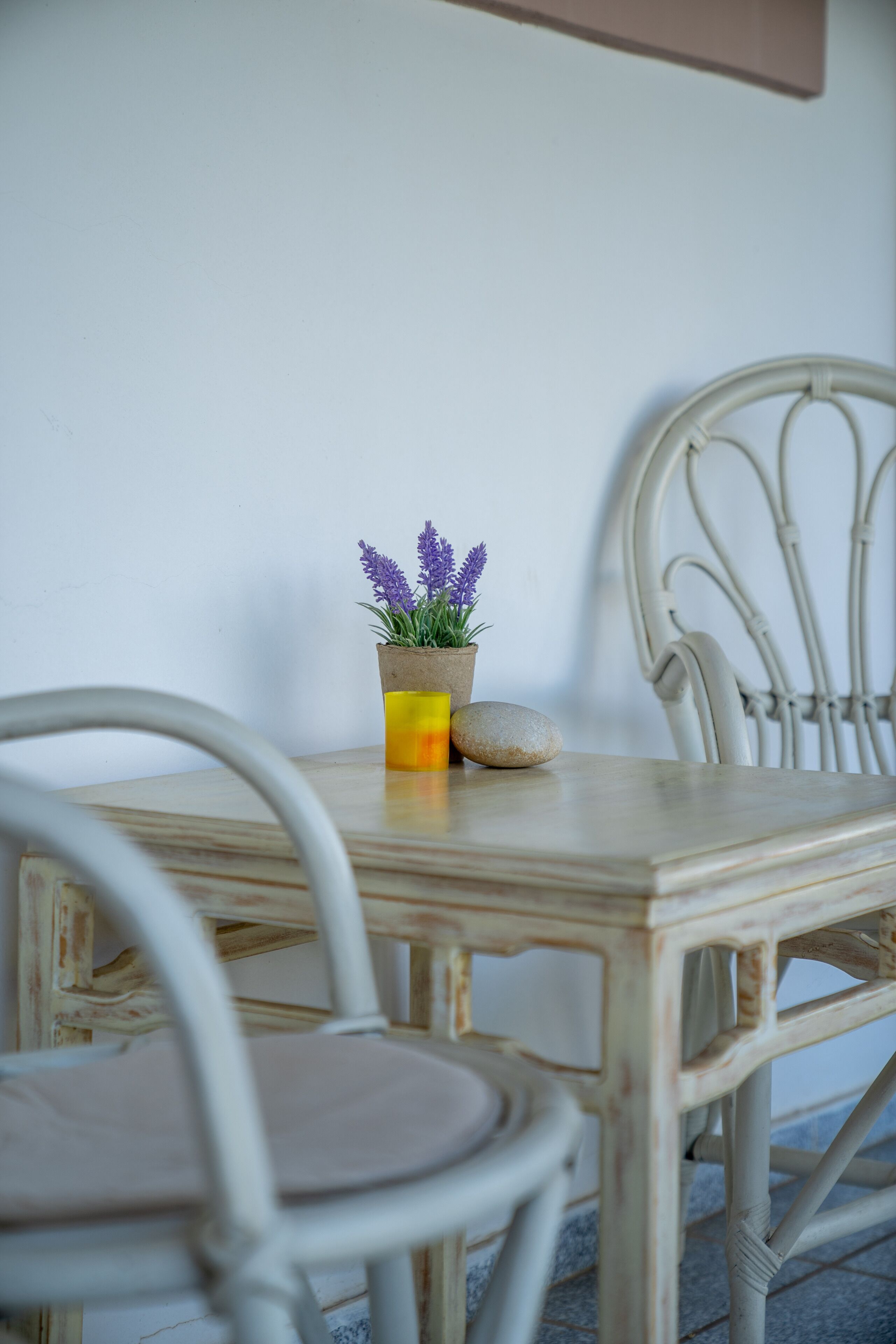 A rustic wooden table with a potted lavender plant and a stone.