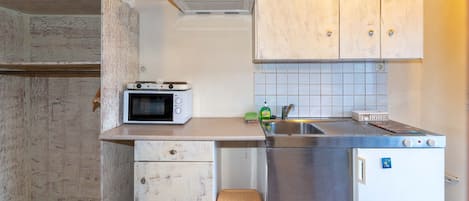 Een keuken met een magnetron, spoelbak en koelkast.