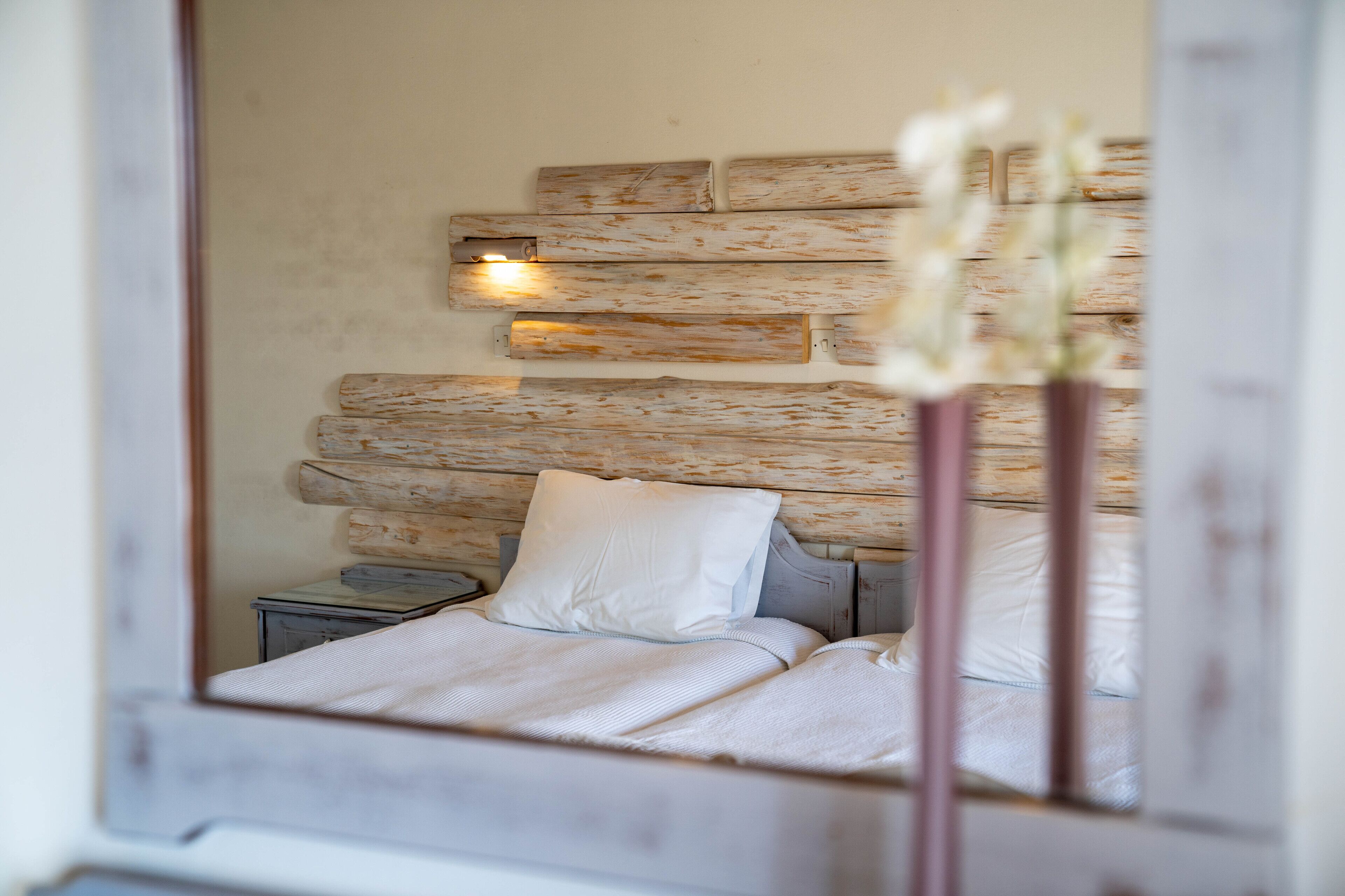Ein Schlafzimmer mit einem rustikalen Holzkopfstück, einem Nachttisch und einem Beistelltisch.