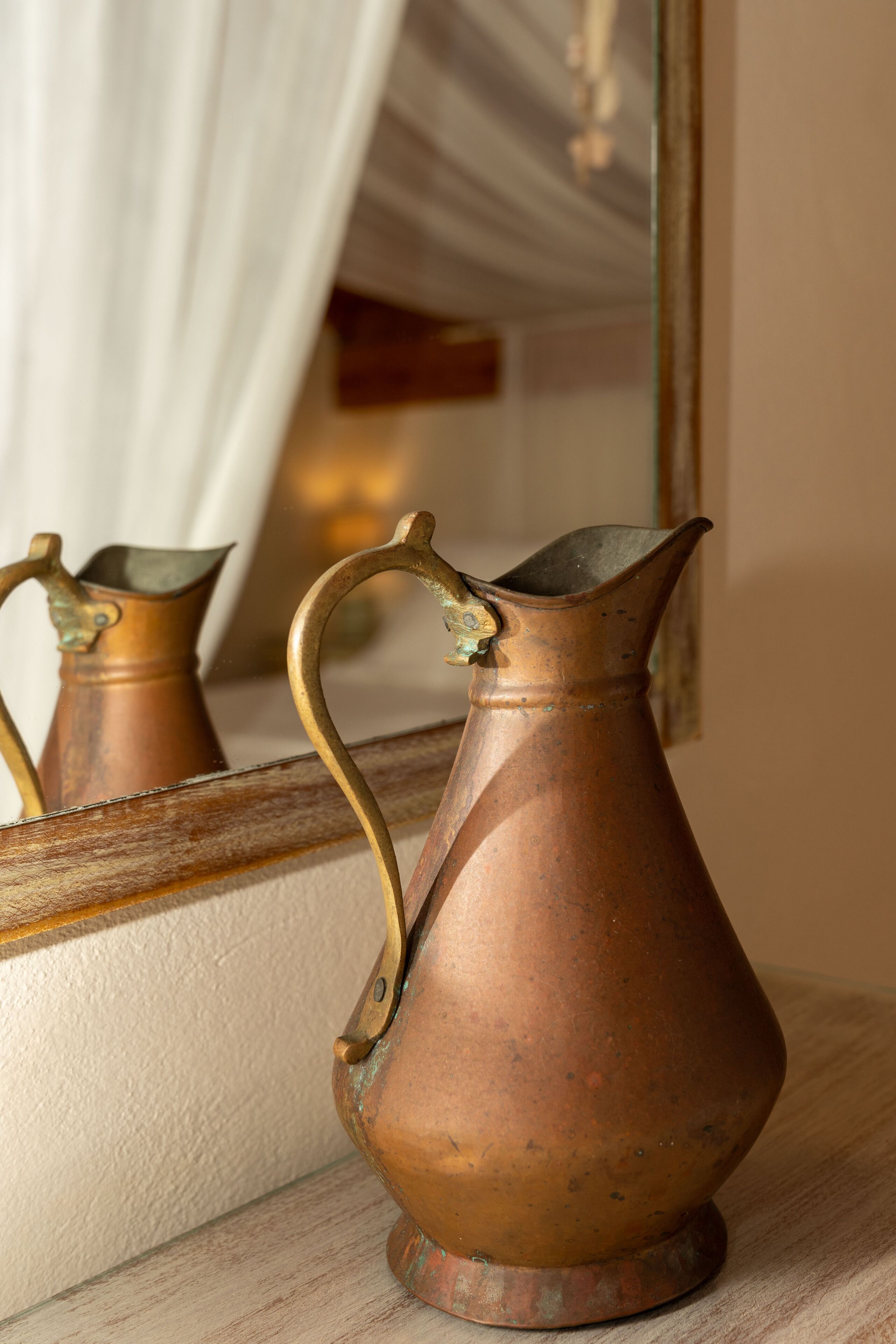 Un jarro de cobre con asa sobre una superficie de madera.