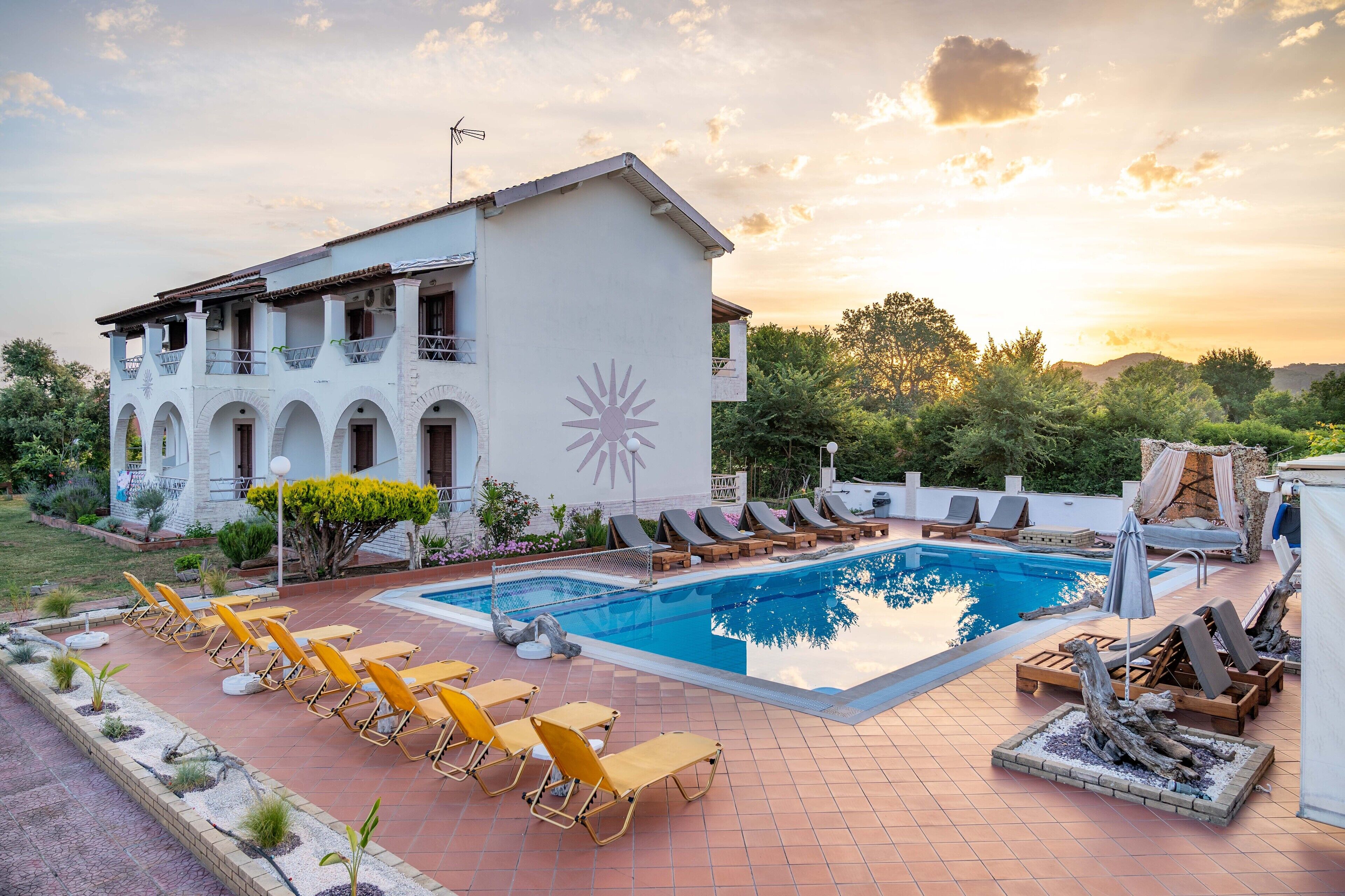 Ein Poolbereich mit Liegestühlen und einem großen Gebäude mit Sonnensymbol.