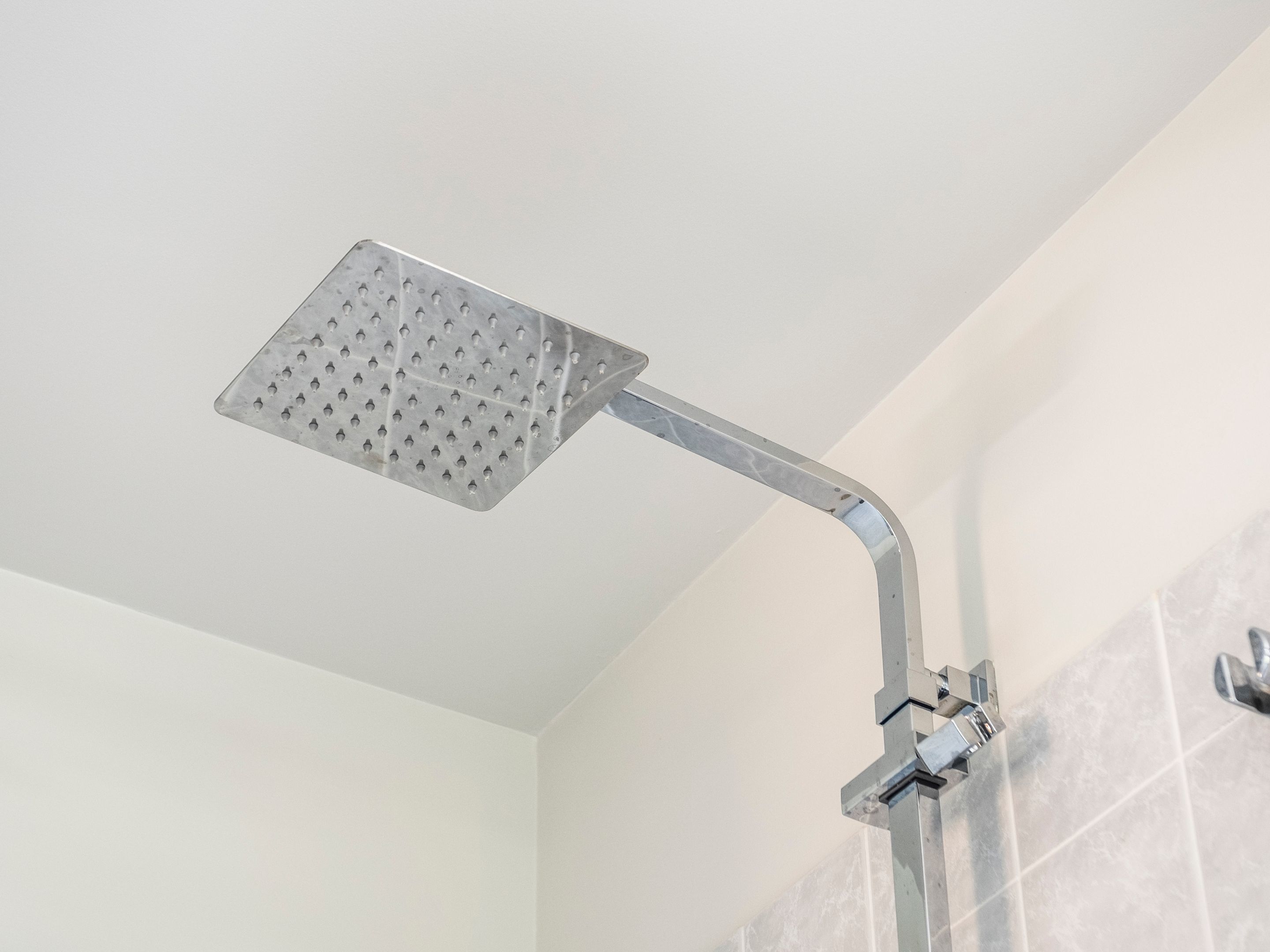 Un cabezal de ducha moderno con diseño cuadrado y múltiples orificios.