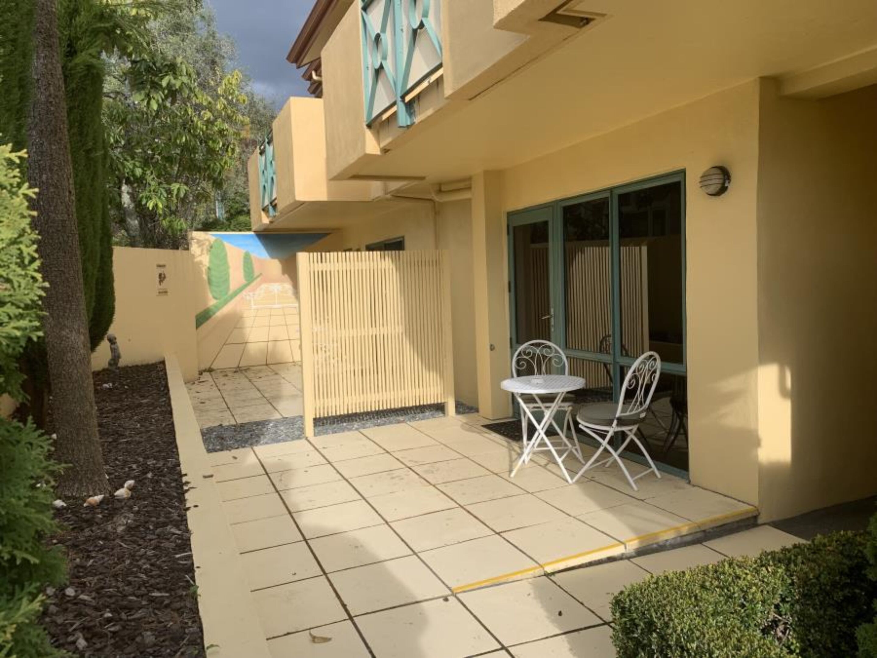 A building with a tiled patio, a fence, and a small table with chairs.