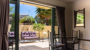 Una habitación con puerta de vidrio corredera que da a un patio con sofá, sillas y una mesita.