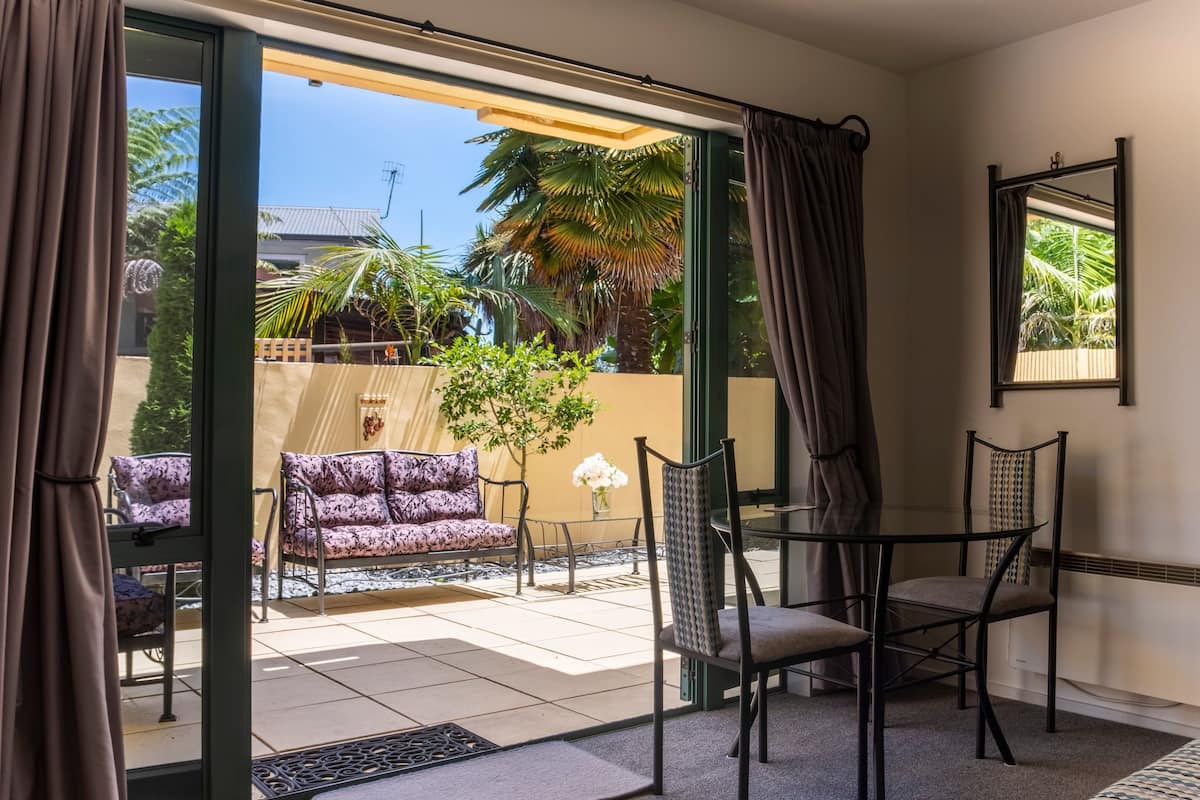 A room with a sliding glass door leading to a patio area with a sofa, chairs, and a small table.