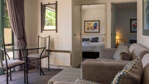 Una habitación acogedora con una mesa de vidrio, un sofá y una cama con ropa de cama estampada.