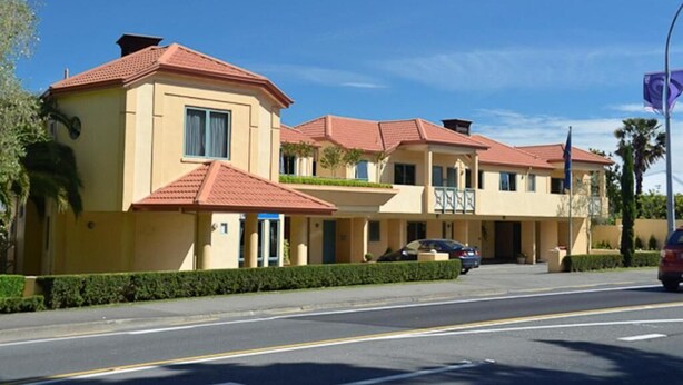 Un hotel de varios pisos con fachada amarilla y techos de tejas rojas.