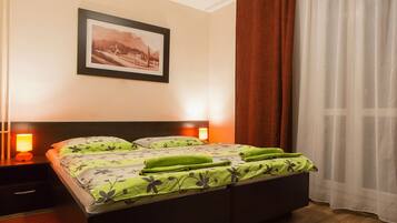 Un dormitorio con cama, mesita de noche, un cuadro enmarcado en la pared y una ventana con cortinas.