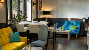 Una sala de estar moderna con un sofá amarillo, un sofá azul y un comedor con una mesa y sillas.