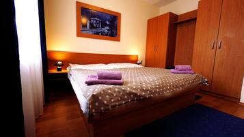 Habitación de hotel con cama de madera, mesita de noche con lámpara, armario y un cuadro en la pared.