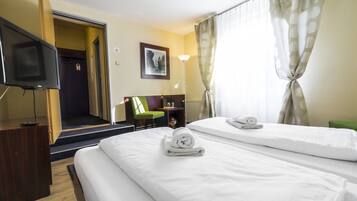 A hotel room with two beds, a TV, a desk, and a chair.