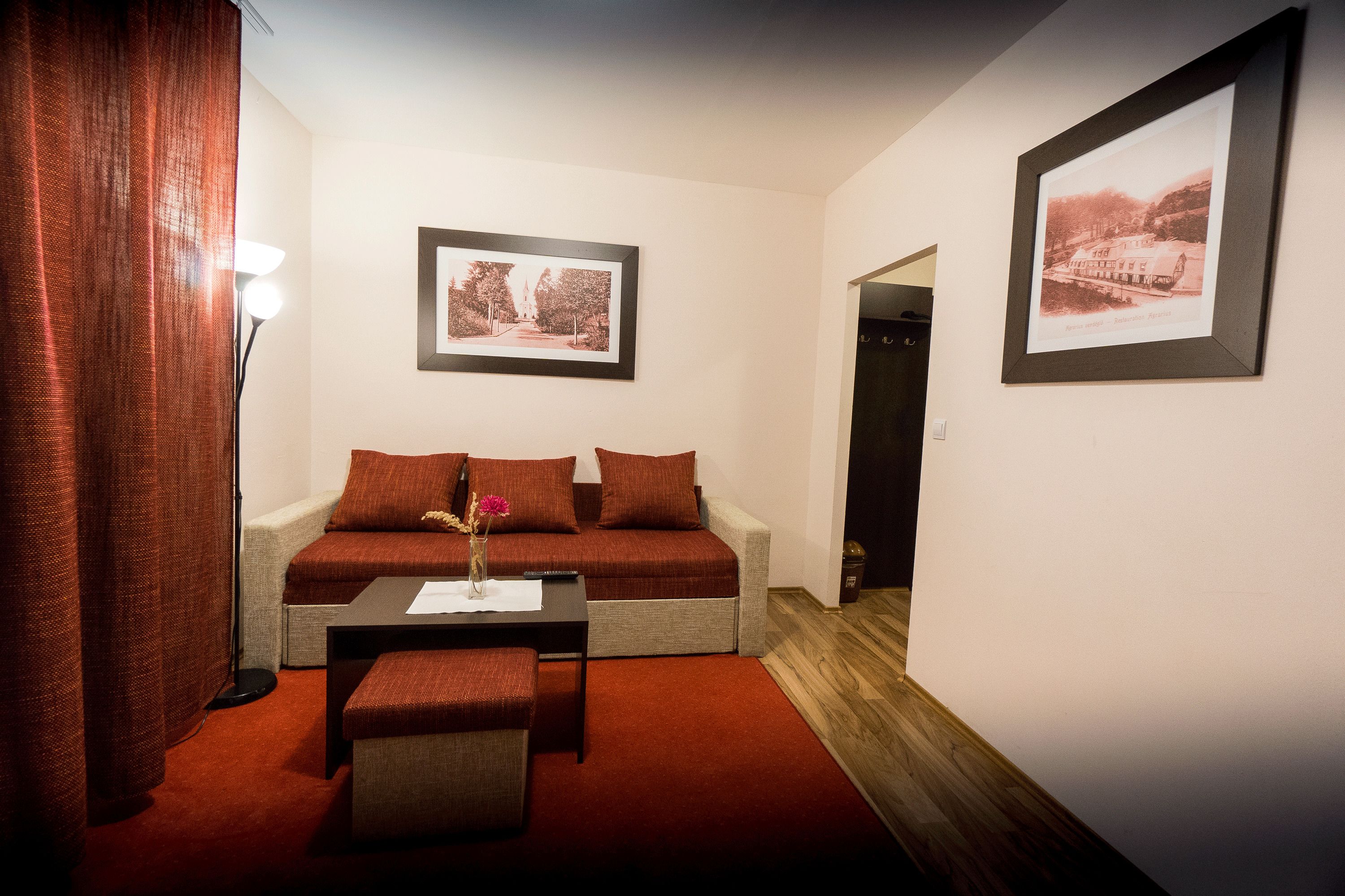 A cozy room with a sofa, a small table with a vase, and two framed pictures on the wall.