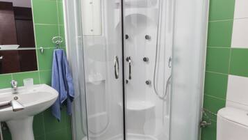A bathroom with a glass-enclosed shower, a sink, and a toilet.