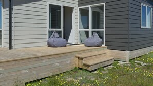 A modern house with a wooden deck, two gray bean bags, and a clear view of the front door. - Manuka Retreat (Ben Ohau)