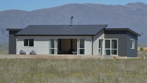 A modern two-story house with a flat roof, large windows, and a chimney. - Manuka Retreat (Ben Ohau)