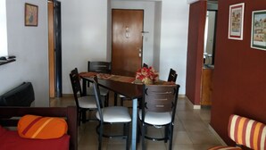 A dining area with a wooden table, six chairs, a decorative vase, and a hanging light fixture. - Como en casa (Rosario)