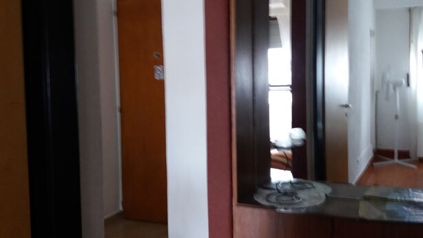 A hallway with a wooden door, a white wall, and a tiled floor. - Como en casa (Rosario)