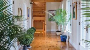 A hallway with wooden beams, potted plants, and framed pictures on the walls.