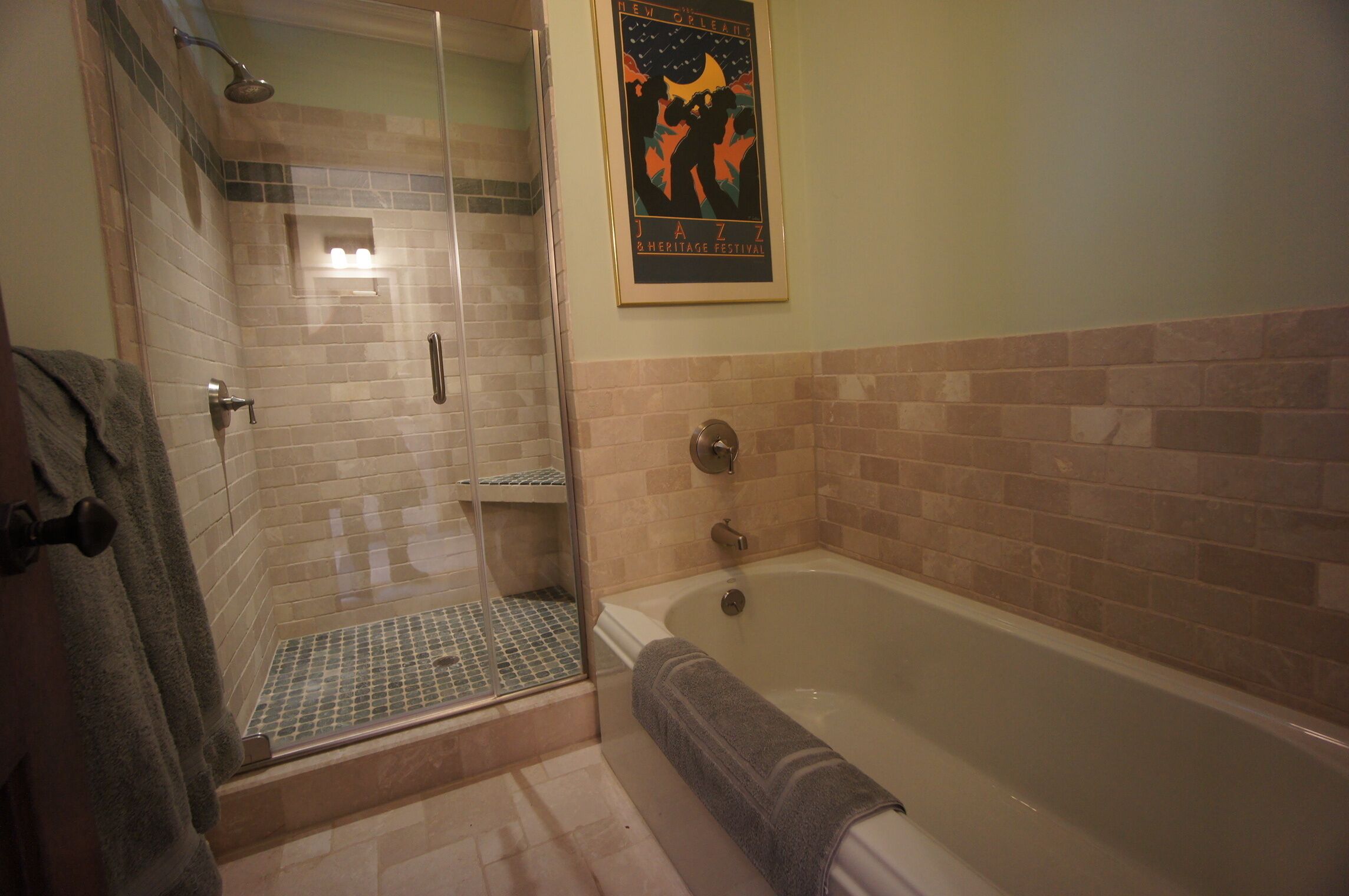 Een badkamer met een douche met glazen wand, een bad en een poster aan de muur.