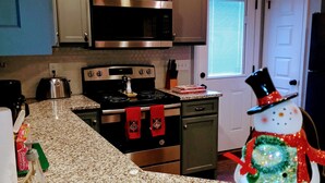 A kitchen with granite countertops, stainless steel appliances, and a decorative snowman figure. - Kathy's Kottage. Bungalow on the side of Missionary Ridge, Furry Friends Welcome (Chattanooga)
