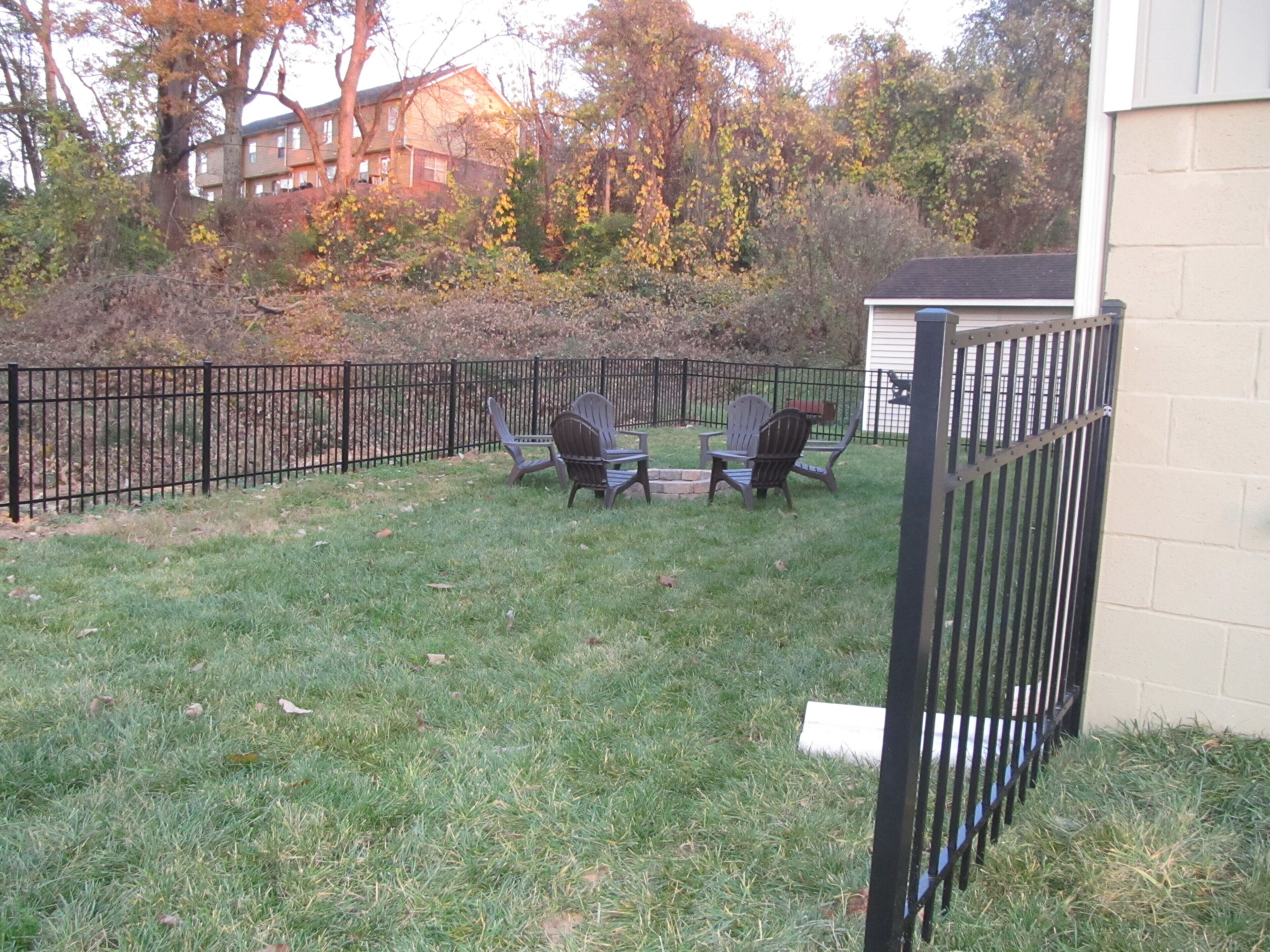 A fenced backyard with two Adirondack chairs and a small table.