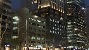 Een modern hotelgebouw met meerdere verdiepingen, verlichte ramen en een opvallend bord bovenop.
