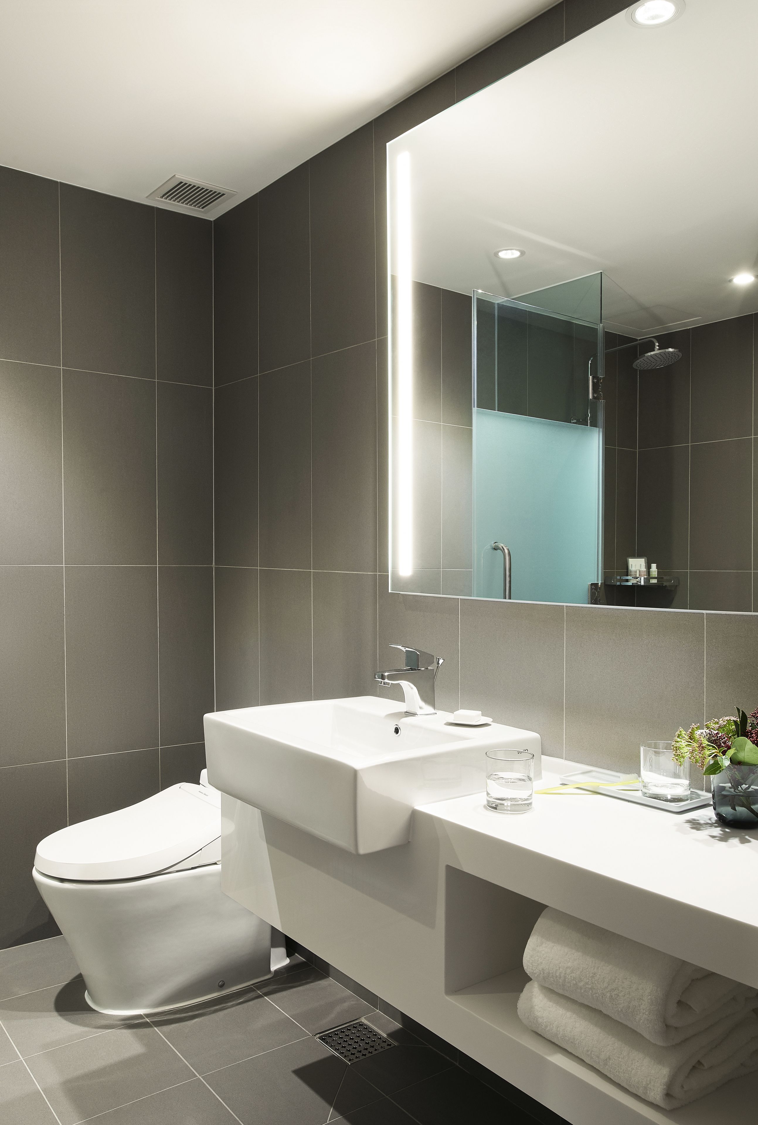 Een moderne badkamer met een wit wastafel, spiegel en toilet.