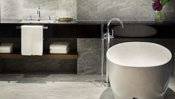 A modern bathroom with a freestanding bathtub, a vanity with a mirror, and a towel rack.