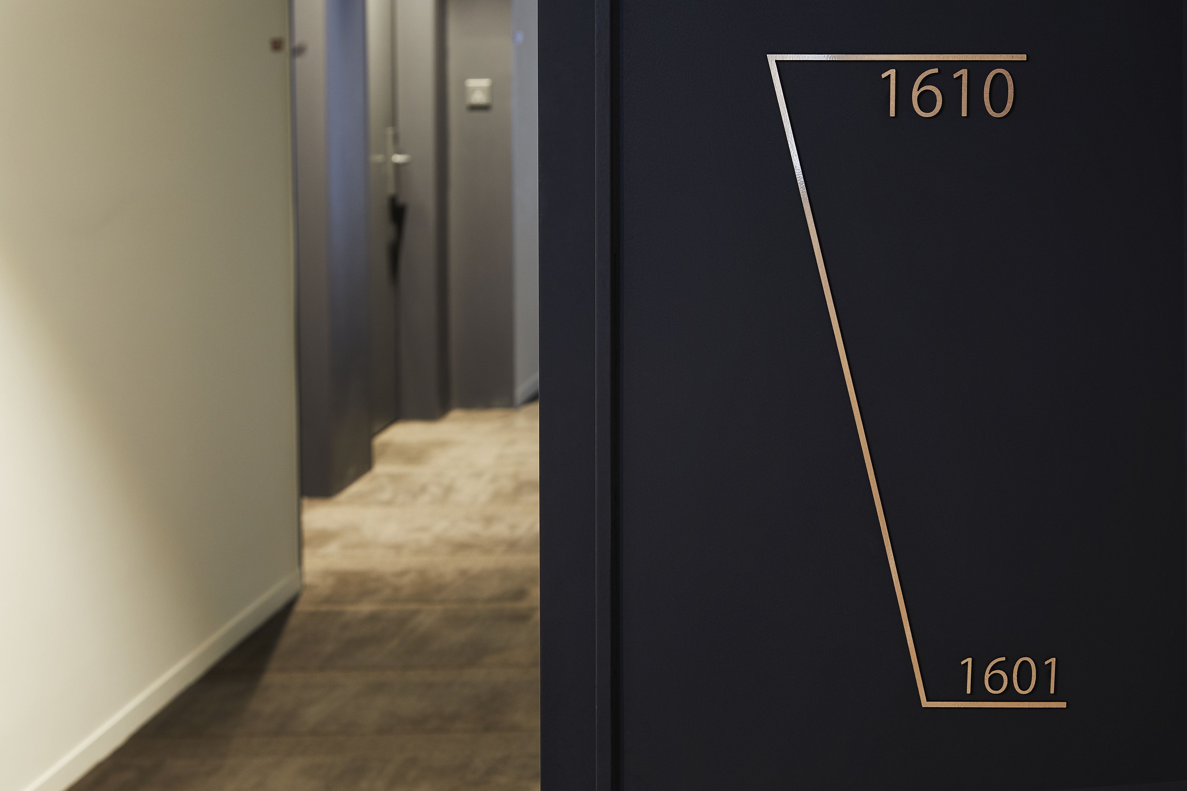 A hallway with a carpeted floor and a door with the numbers 1610 and 1601 on it.