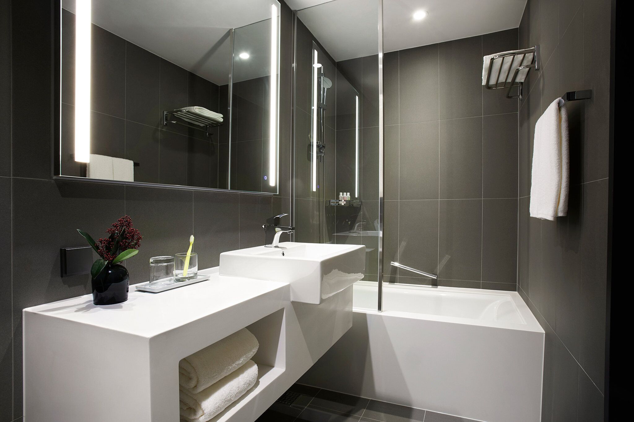 A modern bathroom with two sinks, a large mirror, and a bathtub.