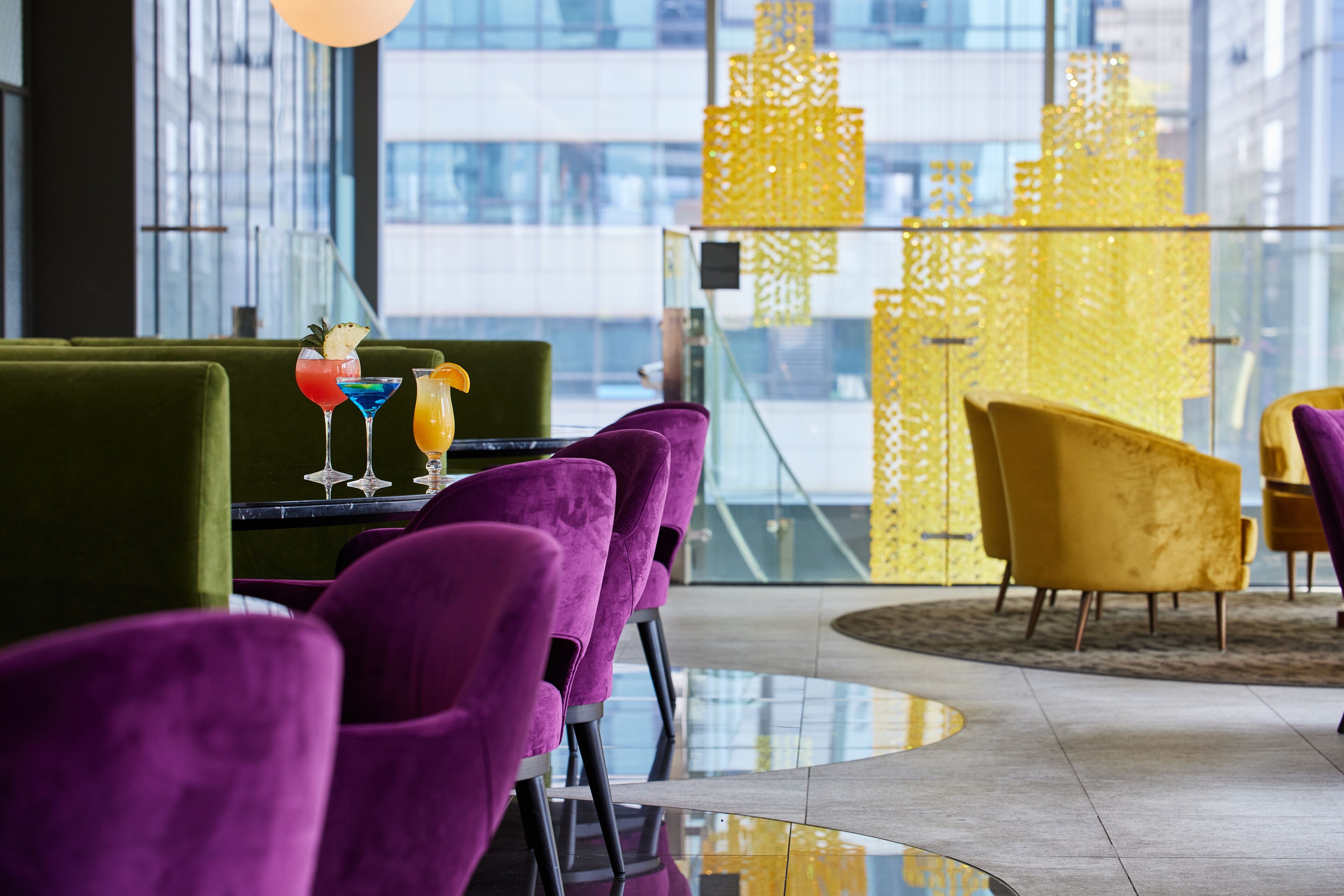 A modern dining area with purple chairs, a glass table, and yellow decorative elements.