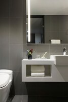 Un baño moderno con un inodoro blanco, un lavabo blanco y un espejo sobre el lavabo.