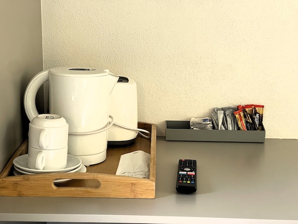 A coffee maker, a remote control, and a tray with a cup and saucer on a table. - Northside Hotel Albury (Lavington)