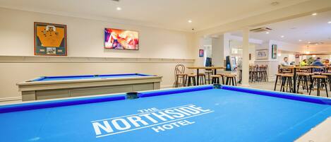 A pool table with "The Northside Hotel" branding, a billiards table, and a bar area with stools and tables.