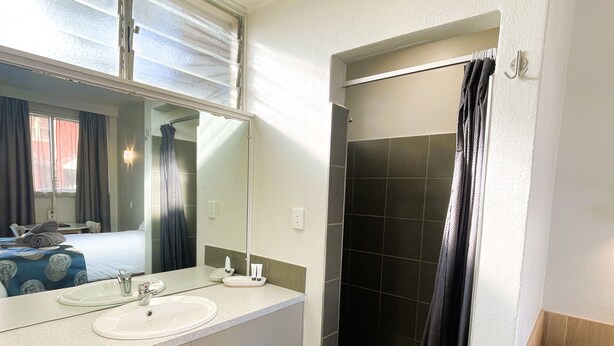 A bathroom with two sinks, a shower, and a mirror. - Northside Hotel Albury (Lavington)