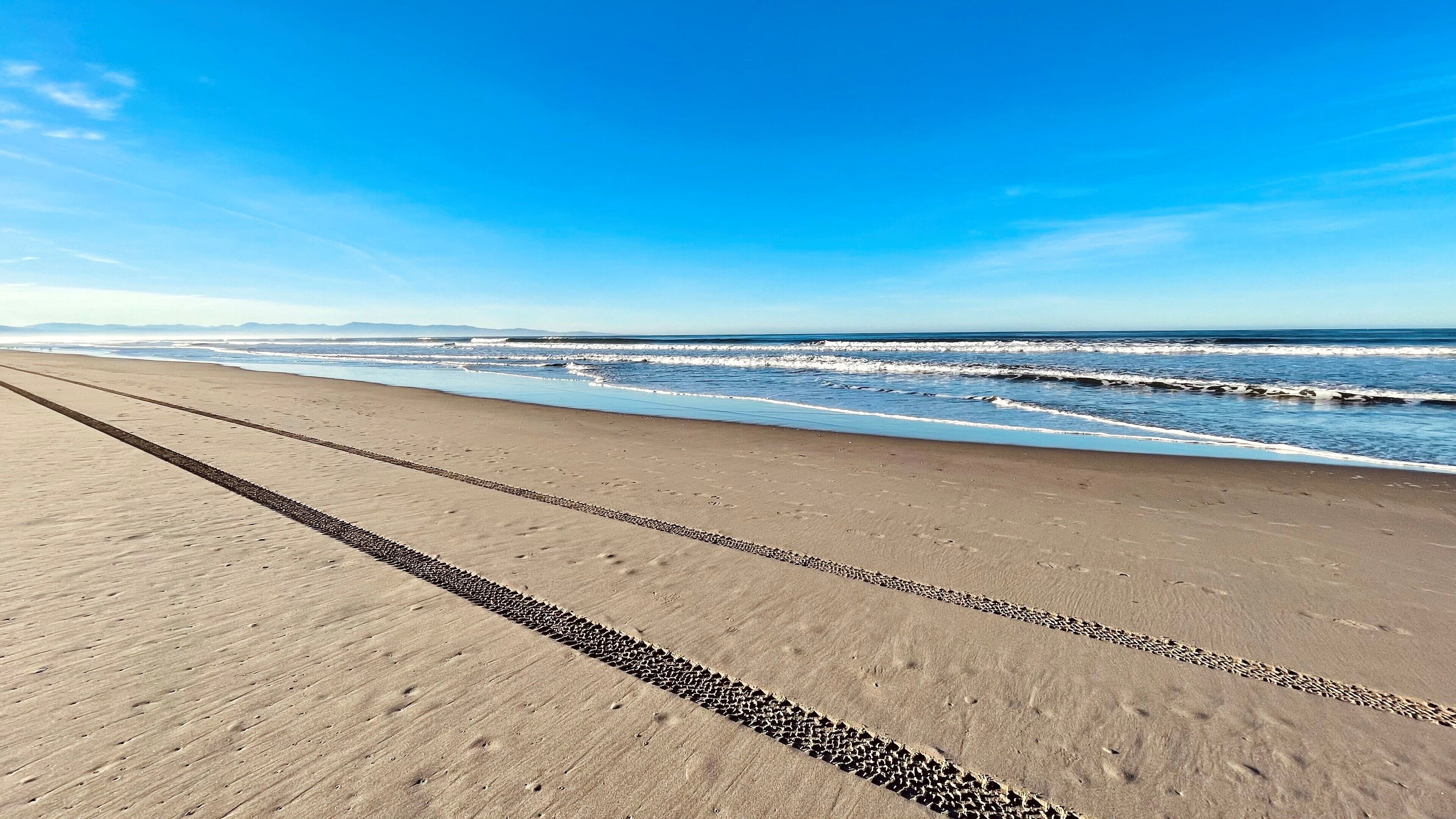 Une plage avec un ciel dégagé et des vagues.