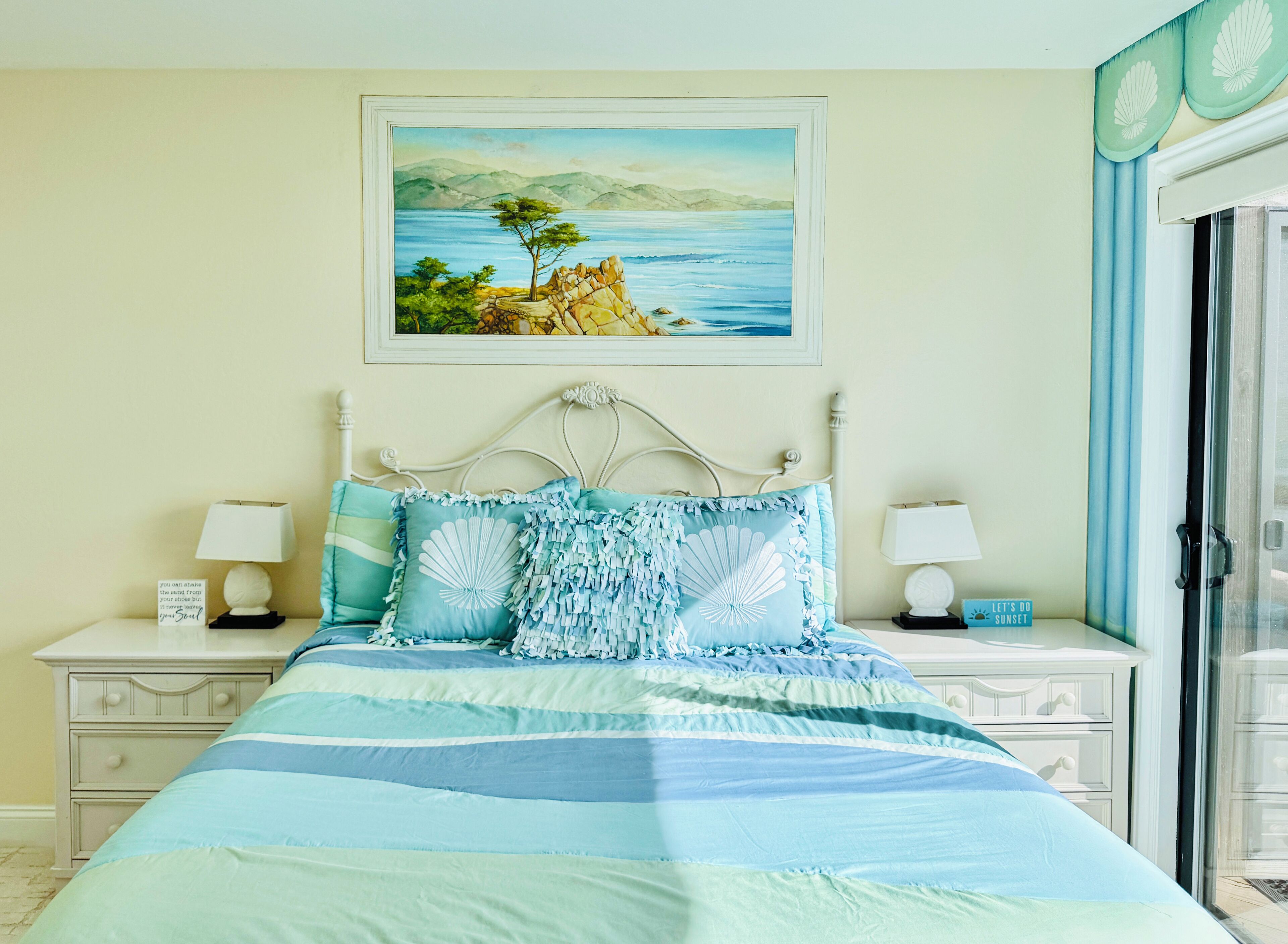 Quarto com cama, duas mesas de cabeceira, um criado-mudo, um quadro e uma janela com cortinas.