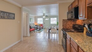 A spacious kitchen with a dining area, a living room, and a ceiling fan.