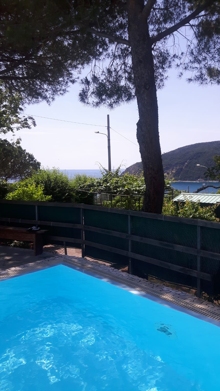 A swimming pool with a view of the sea and hills in the background.